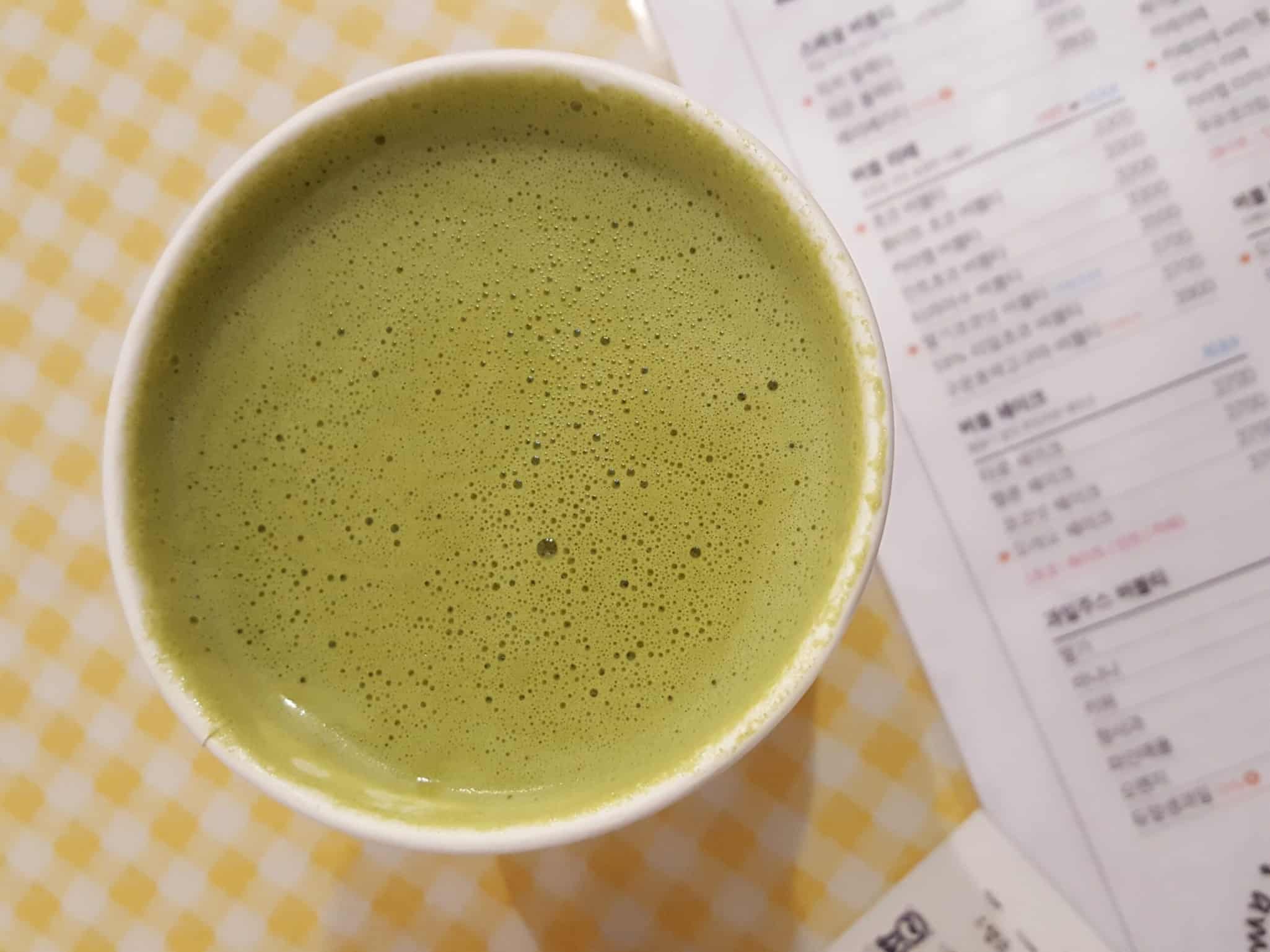 Boisson verte protéinée sans additifs ni édulcorants sur une nappe à carreaux, reflétant la qualité Protéalpes.