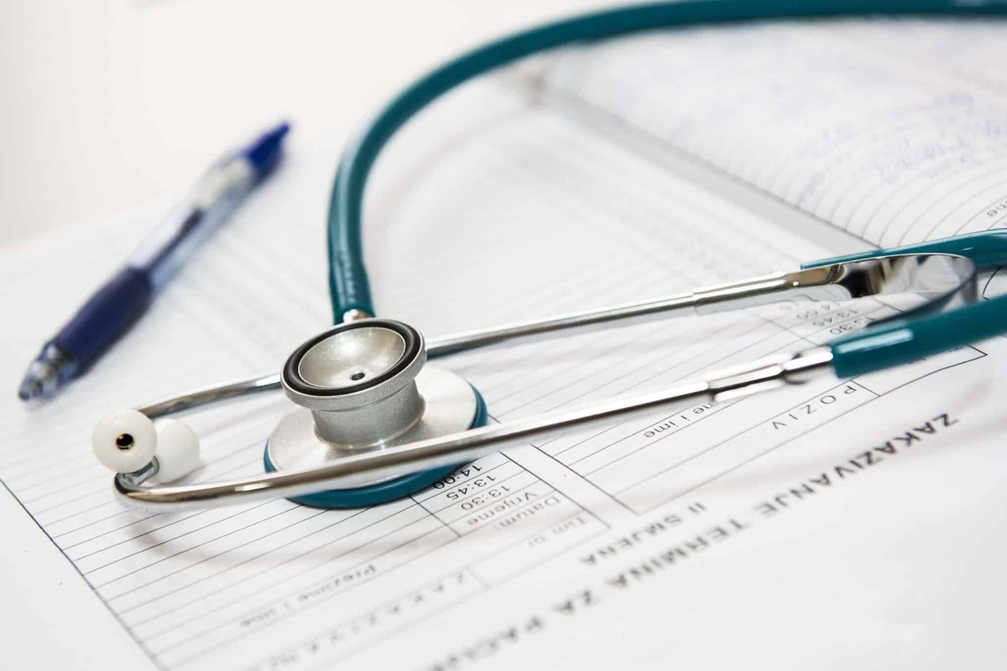 Stéthoscope et stylo sur documents médicaux, symbolisant la santé et la qualité, valeurs clés de Protéalpes.