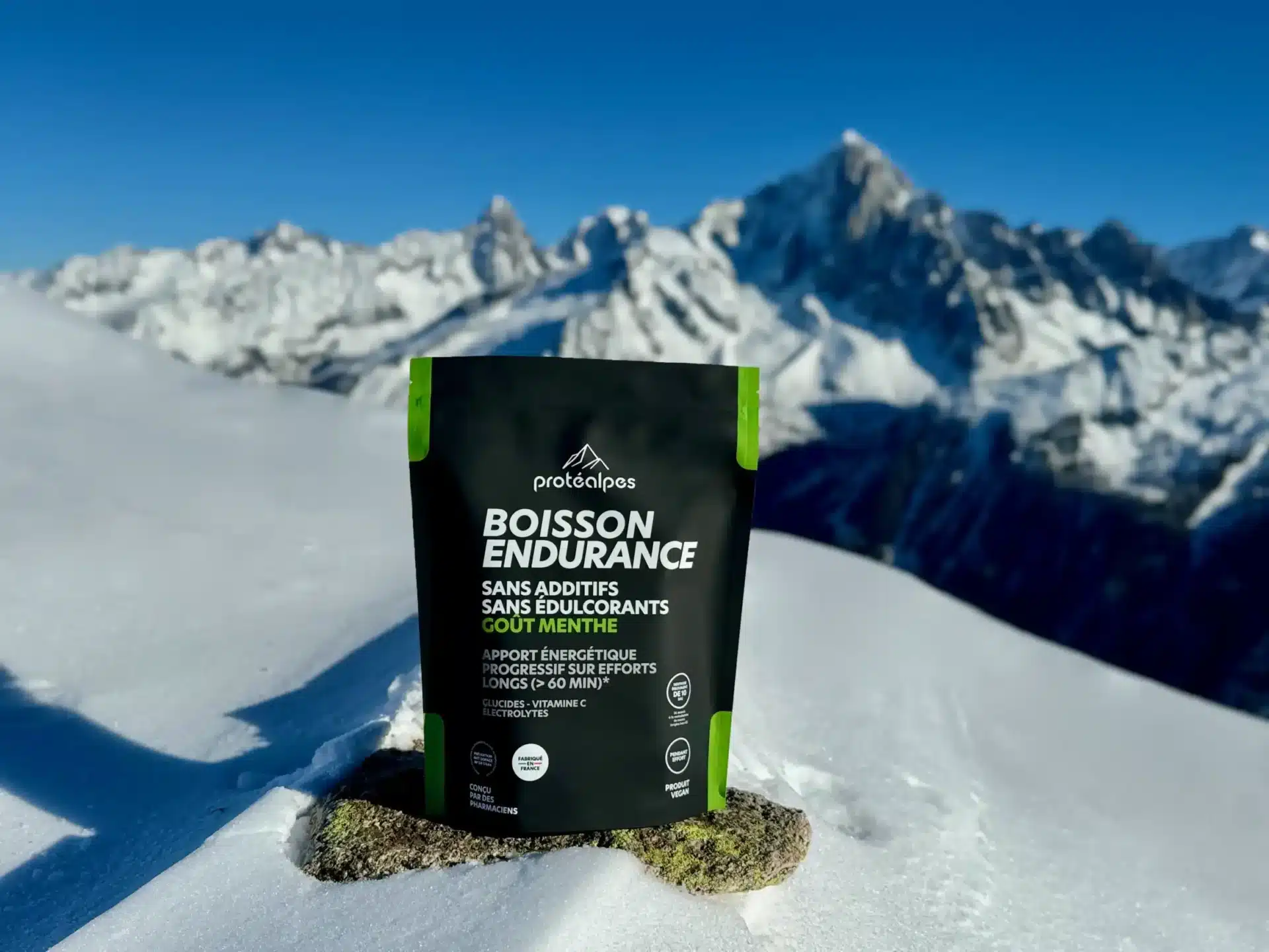 Boisson Protéalpes sans additifs ni édulcorants, posée sur neige, montagne en arrière-plan, nutrition sportive naturelle.
