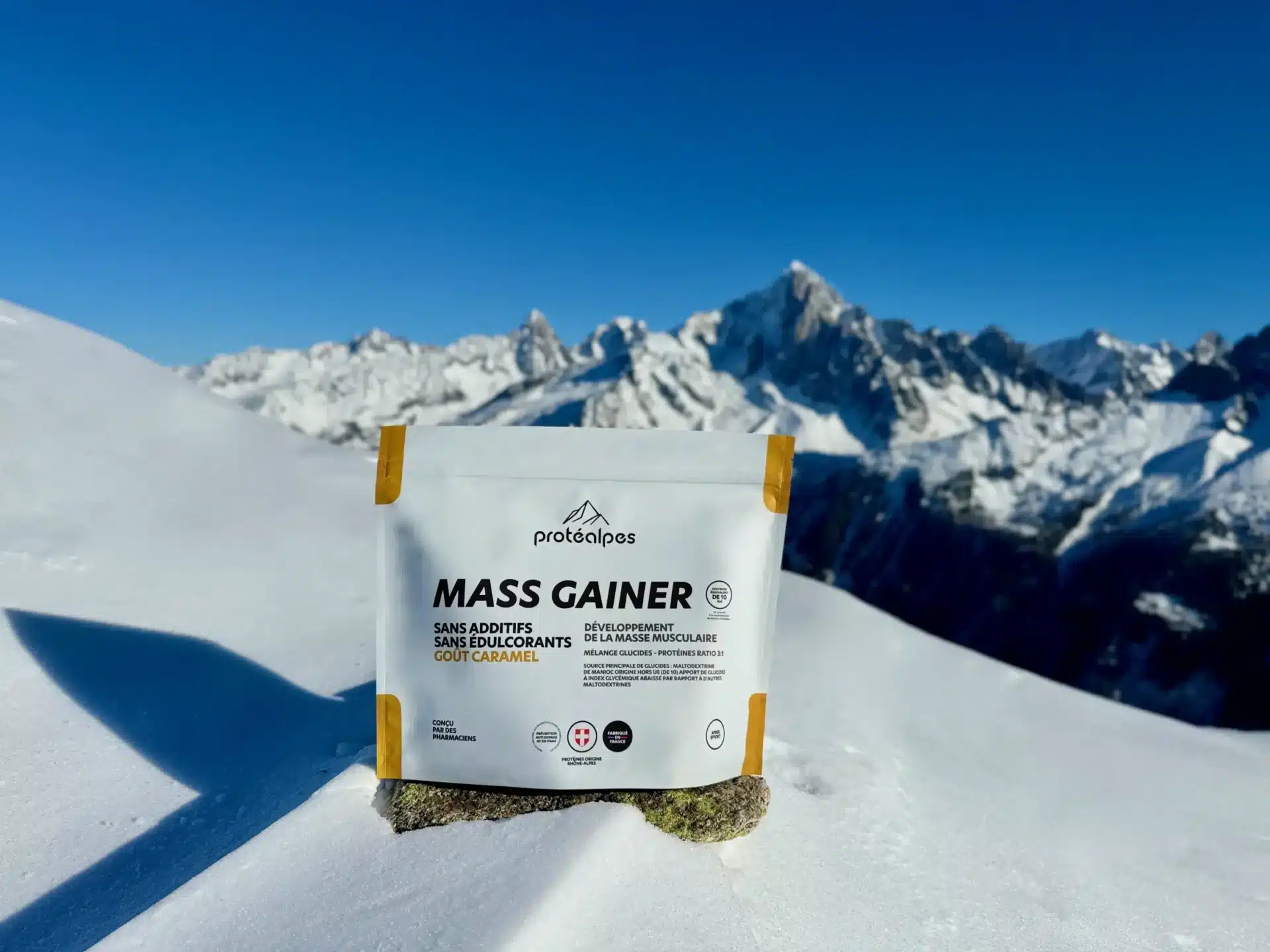 Pack de Mass Gainer Protéalpes sans additifs, sans édulcorants, goût caramel, dans un paysage enneigé de montagne.