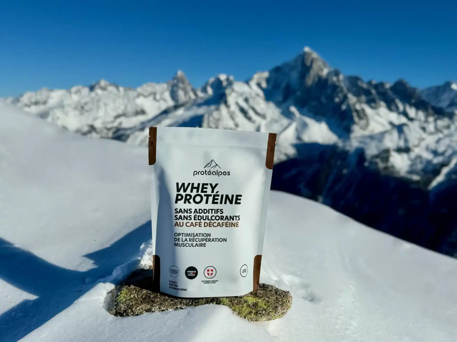 Pack de Whey Protéine Protéalpes sans additifs ni édulcorants, sur fond de montagnes enneigées, symbolisant pureté et qualité.
