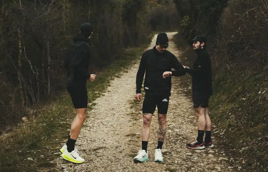 Trois coureurs s'entraînent sur un chemin forestier, symbolisant la détermination et la nutrition naturelle avec Protéalpes.