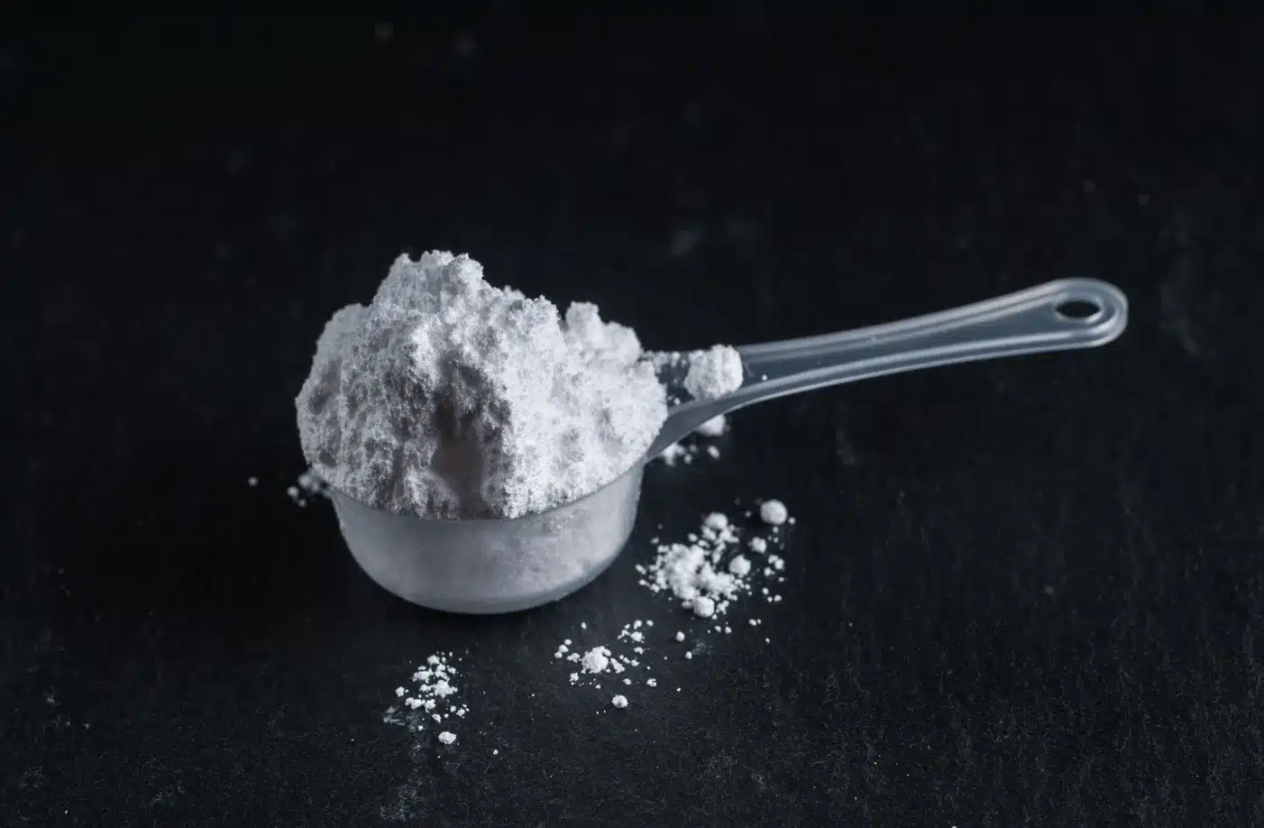 Maß für gesundes Proteinpulver Protéalpes, ohne Süßstoffe oder Zusatzstoffe, auf dunklem Hintergrund.