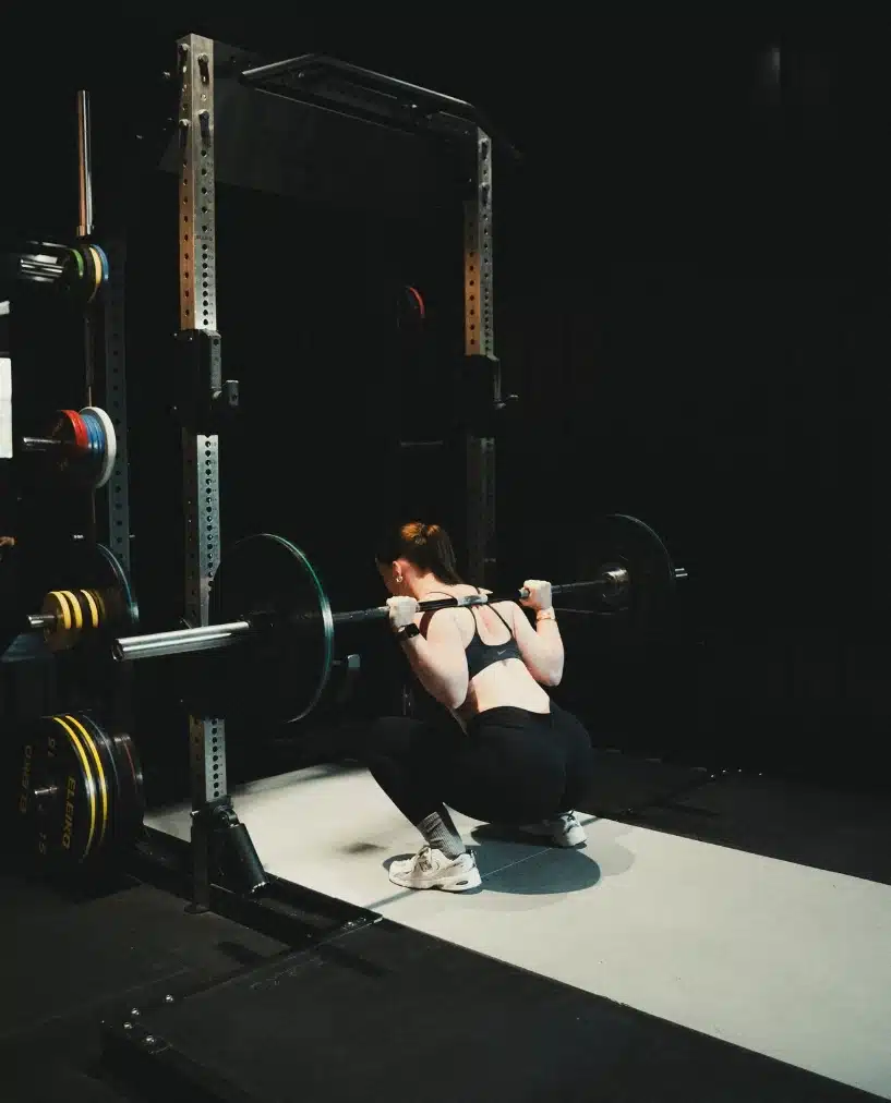 Femme faisant des squats avec haltères, représentant la force et l'endurance, valeurs de la nutrition sportive Protéalpes.