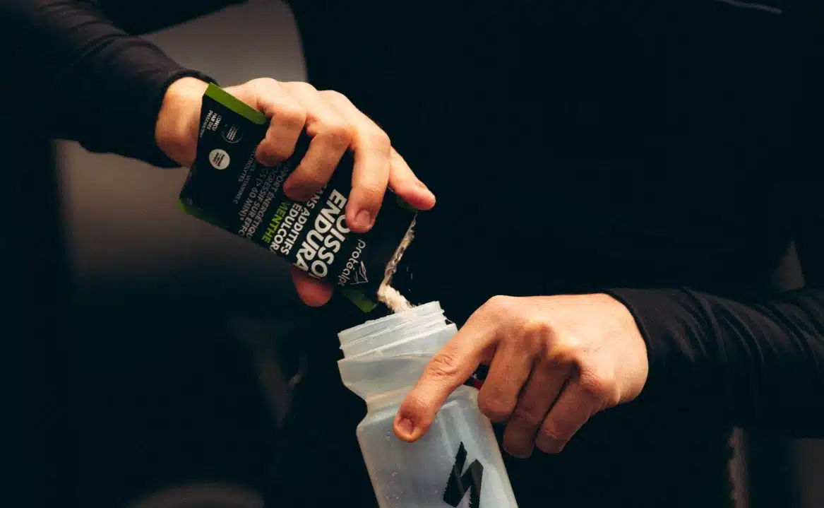 Athlète préparant un shaker avec un produit Protéalpes. Nutrition sportive sans édulcorants ni additifs.