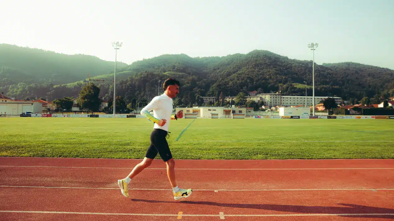Un athlète court sur une piste, entouré de verdure, symbolisant la nutrition sportive pure et sans additifs de Protéalpes.